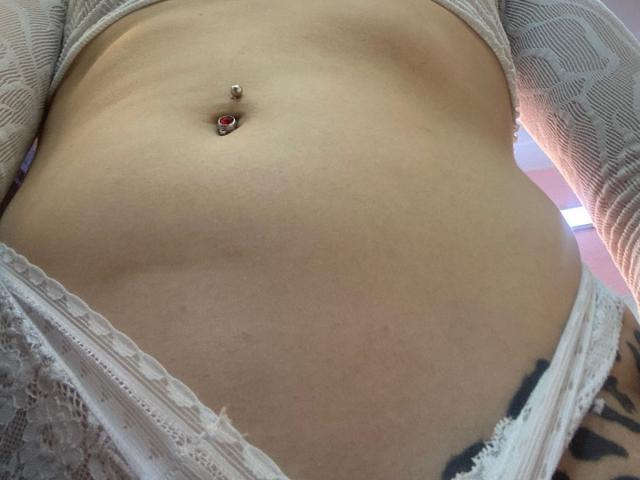 LivelyVanderWood's flat stomach with a red jewel belly button piercing, wearing lace-trimmed white underwear, showing a tattoo on the right side.