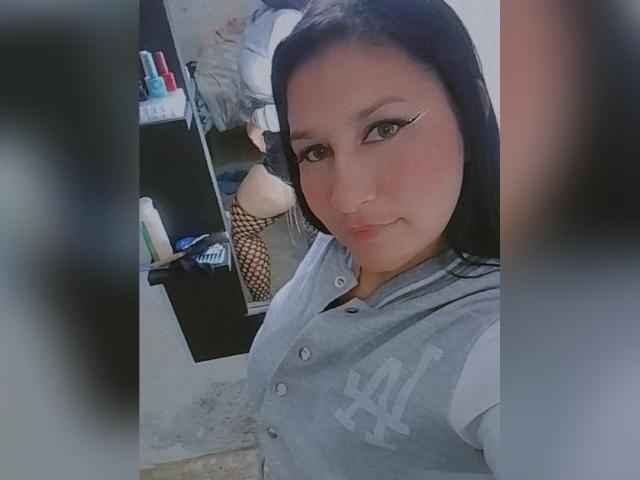 NikolSensual69 ha i capelli scuri, indossa una maglia grigia dei New York Jets, con un trucco occhi a eyeliner ad ali di gabbiano, in un selfie allo specchio che mostra il suo viso e la parte superiore del corpo, con un sorriso appena accennato..
