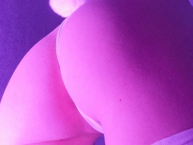 ExcitedBlizzard's butt in white panties, illuminated by purple light. The skin is smooth with a small mole on the right cheek. A fluffy white tail is visible.
