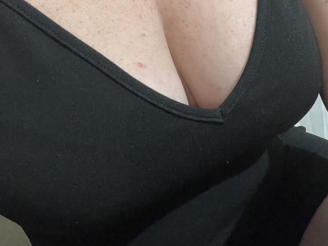 SabrinneSexy's big tits in a black tank top, showing a deep cleavage with freckles on her pale skin. The image focuses on her chest.