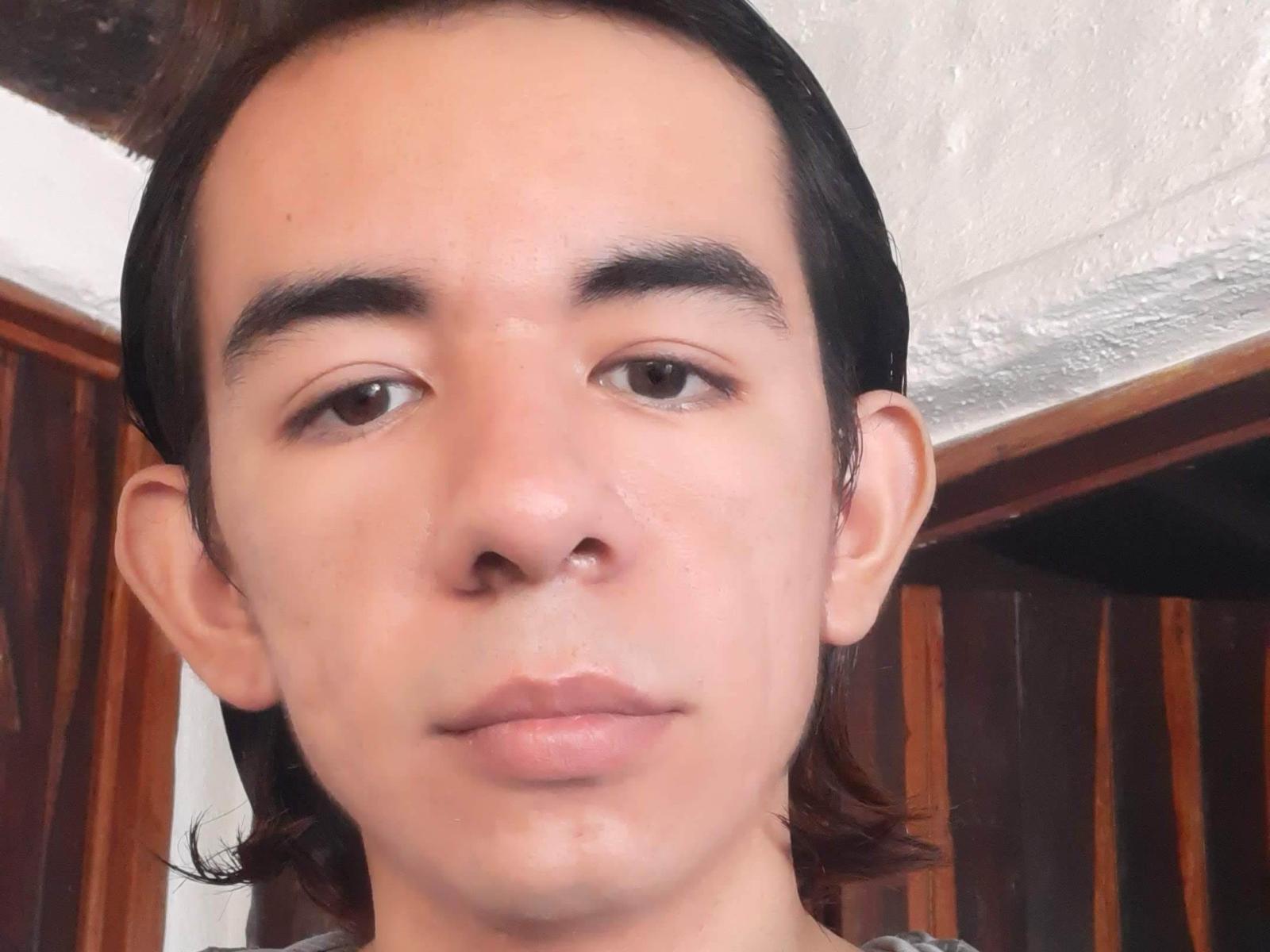 Kaiuwur has a clean-shaven face, brown eyes, and medium-length black hair. His nose is slightly shiny, and he has a neutral expression. He's wearing a shirt.