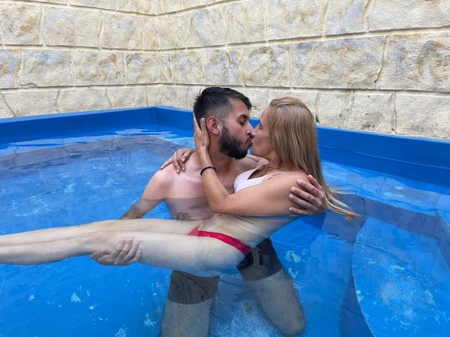 TifanyAndStiven, kissing passionately in a blue-tiled pool. She's in a red bikini, his hands on her ass and tits. He's holding her up, both with wet skin.