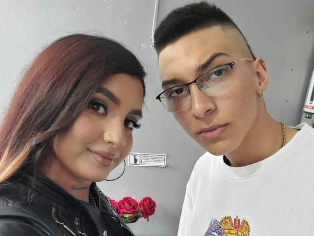 ZafiroModels with dark brown hair and red rose, black jacket, nose ring, and tattoo, next to ZafiroModels with short black hair, glasses, white shirt, and gold necklace.
