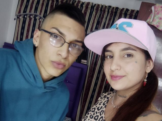 ZafiroModels with glasses, teal hoodie, and short dark hair, next to ZafiroModels in pink cap, leopard print shirt, and red earrings, showing a small mole on her cheek.