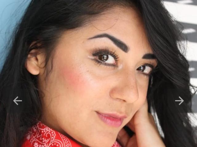 SophiQueen's face, dark hair, brown eyes, slightly wavy, thick eyebrows, pink blush, subtle smile, red bandana, left hand touching cheek, right arrow pointing at eyebrow, left arrow pointing at eye.