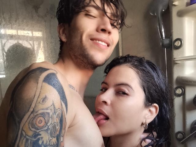 HottersTeam with tattoos on the left, shirtless, smiling, has wet dark hair and earrings. HottersTeam on the right, tongue out, licking left chest, wet black hair.