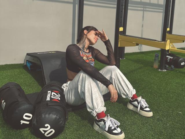 Stylized logo with a bold, geometric design. Features a large, flat, rectangular shape with a small, white emblem at the bottom. Colors are muted, with a slight red accent.