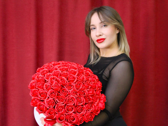 PollyBracy with red roses, black sheer dress, red lipstick, holding a massive bouquet of red roses, smiling, blonde hair, sexy, cute, attractive.