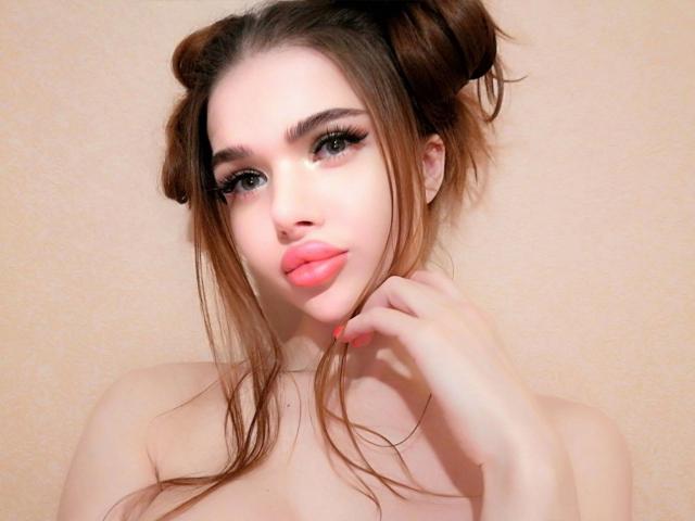 KatrinaBonita-hot with double buns, full pink lips, long eyelashes, fair skin, and pink nails, touching her neck, topless, showing small tits, brown hair, and a cute face.