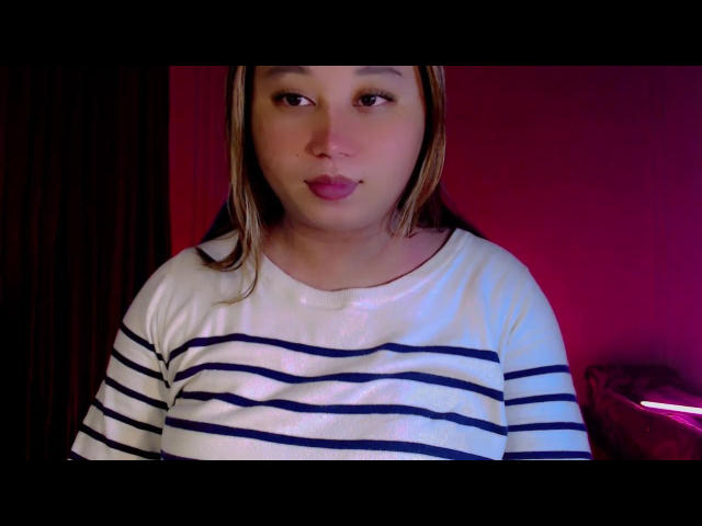 SereiaRedfield with medium skin, brown eyes, and straight brown hair, wearing a white striped shirt, has pouty pink lips, and is looking slightly to the left.