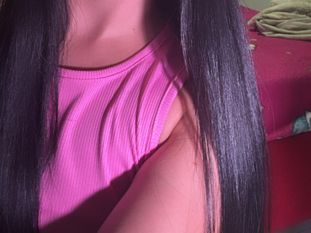 SarahGood's pink ribbed tank top, showing her sideboob and armpit, with long straight black hair in the foreground, under soft pink lighting.