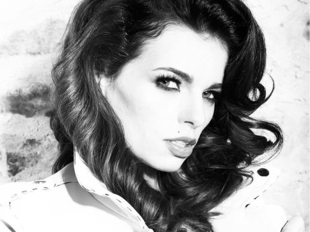 LillaGrey's pouty face, wavy dark hair, and smoky eye makeup are prominent in this black-and-white shot. Her tits are slightly visible under a white shirt.