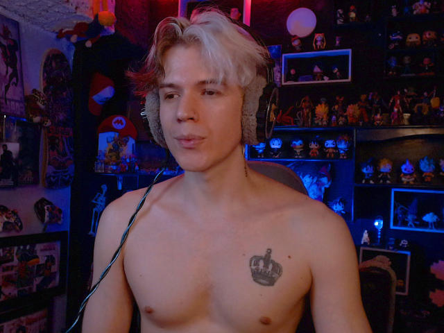 Shirtless RedTemptation with a crown tattoo on his chest, wearing large headphones, has light blonde and brown hair, and a slightly confused expression. Blue and red lighting.