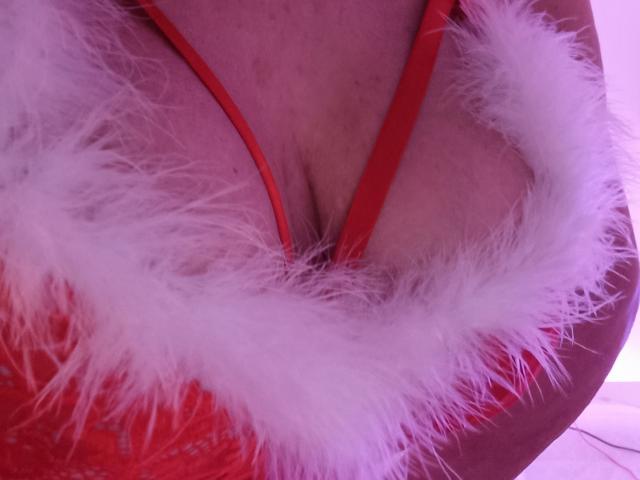 Cateys69's red lingerie with white fluffy trim, showcasing her large tits, highlighted by the red straps and pink lighting.