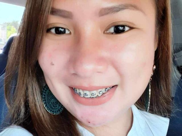 EmmaRose69's smiling face with straight brown hair, brown eyes, and a silver nose ring. She has a black mole on her left cheek and metallic teeth.