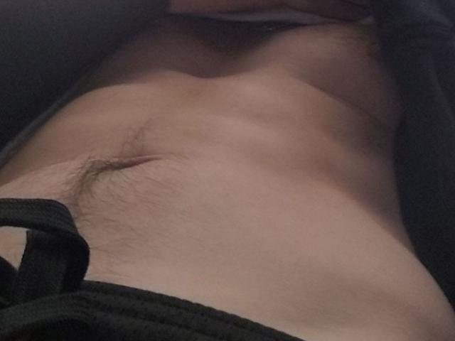 BigCockJoe69's bare, slightly hairy, toned belly with a small, healed scar just above the navel, showing a bit of dark pubic hair. Lower black clothing is visible.
