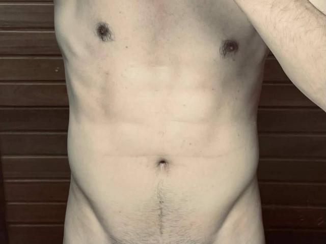 MasterDonJuan's bare, light-skinned torso shows a flat, muscular stomach with visible abs, small dark nipples, and a slight trail of pubic hair. His right arm is partially visible.