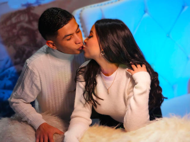 KylieAndJustin kissing, both in white turtlenecks, KylieAndJustin's dark hair and Justin's short hair, Justin's hand on KylieAndJustin's fluffy white butt, blue light in background.