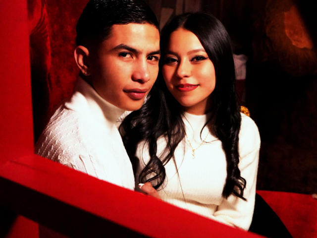 KylieAndJustin, a cute Asian couple, in a red room, with KylieAndJustin's long black hair and white sweater, and Justin's short black hair and white turtleneck.