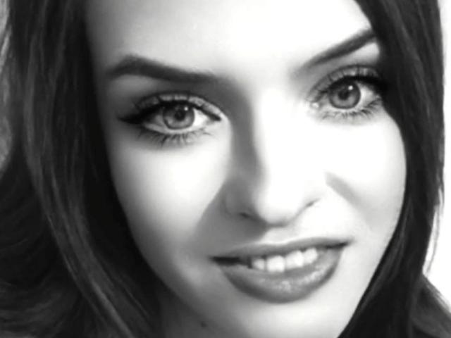 Foto em preto e branco de LissaMeow, com olhos grandes e atraentes, lábios cheios e cabelo escuro e ondulado, mostrando um sorriso sutil. Seus cílios são longos e proeminentes..