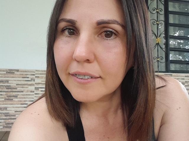 AdelaShery tiene el cabello castaño lacio, ojos marrones y un tono de piel claro. Lleva una blusa negra que deja ver ligeramente sus pechos, y tiene brackets metálicos en los dientes..