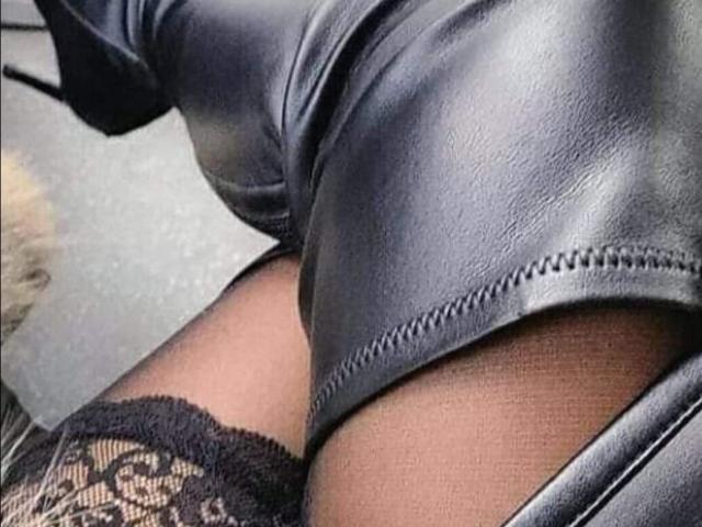 Cateys69's black leather butt cheeks, with a lace thigh-high on one leg, showing a little black panty. Skin is visible between leather and lace.