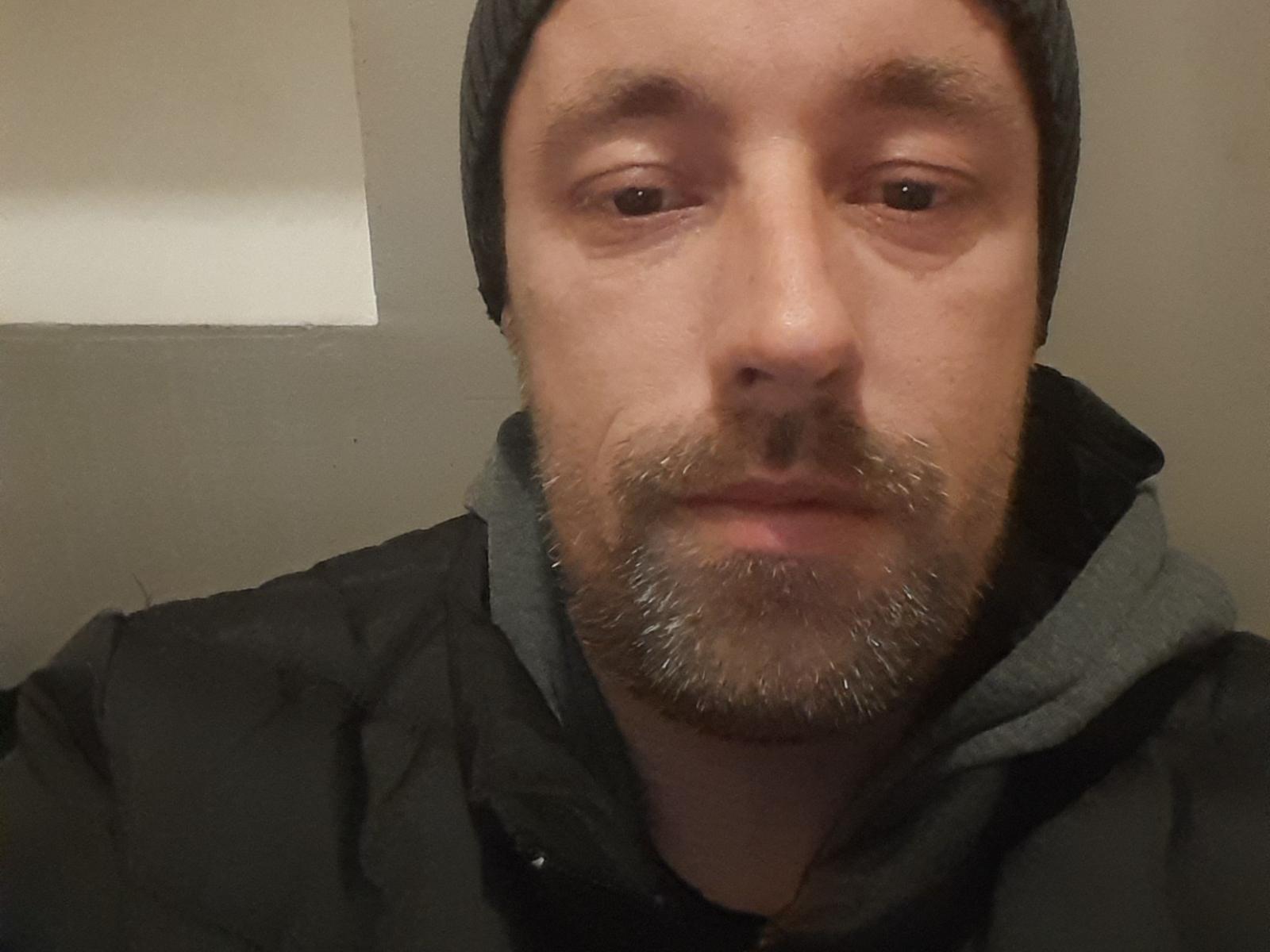 Math69x has a bearded, slightly scruffy face, wearing a gray beanie and black jacket with a gray hoodie underneath. His brown eyes look directly at the camera.