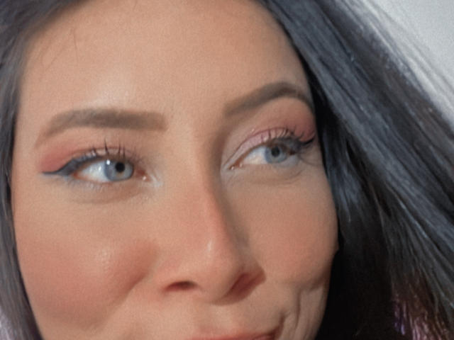 JennyLawry's face, showing blue eyes, pink eyeliner, and dark brown eyebrows, with straight black hair, slightly smiling, and light skin. Boobless, no visible ass or pussy.