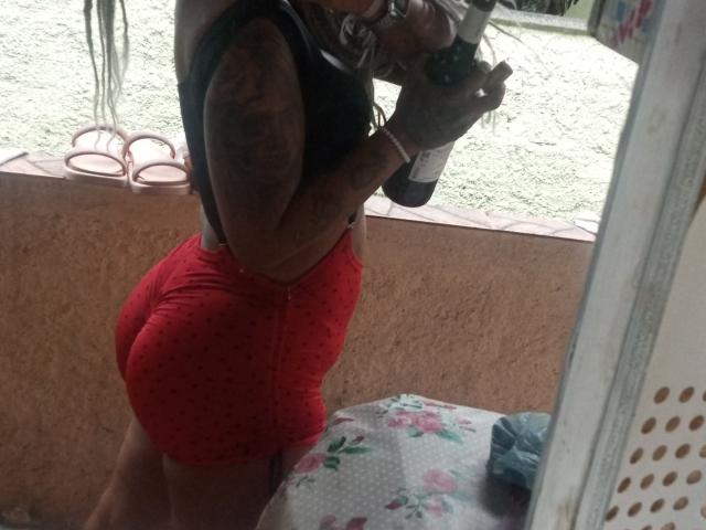 SheaStar with tattoos, wearing a black tank top and tight red polka dot shorts, holding a camera, showing her round ass in a mirror selfie.