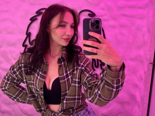 Ornate, bold, flat, stylized lettering with a dark, almost black color on a light pink background. Letters have sharp, angular lines with intricate, web-like patterns in the bottom left.