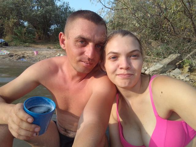 Un ParaFox con capelli castani corti e una carnagione abbronzata, con parte superiore del corpo muscolosa e senza maglietta, tiene una tazza blu, seduto accanto a un altro ParaFox con capelli biondi, top da bikini rosa e piccoli seni..