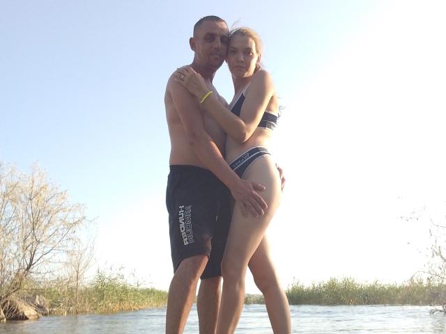 Un ParaFox senza camicia e con la barba si trova dietro una donna bionda in un bikini a righe blu, con il sedere contro il suo inguine, e le braccia avvolte l'una intorno all'altra, vicino a un canale d'acqua..