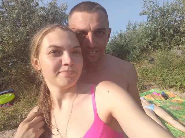 Una foto de ParaFox con cabello rubio y un bikini rosa, y ParaFox con cabello corto y castaño, y sin camisa, de pie detrás de ella. Sus pechos son pequeños, y se puede ver su trasero..