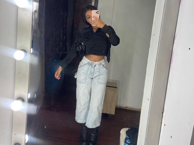 AlessiaFerry, dans un selfie pris dans un miroir, porte un haut noir à manches longues, un jean bleu clair taille haute, des bottes noires et un petit sac à main noir, laissant entrevoir son ventre plat..