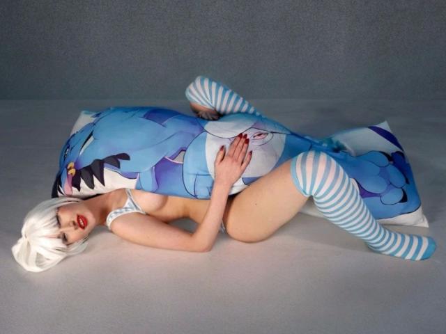 Lynn-Tonic-hot with white wig, red lipstick, and striped blue-white socks, lying on blue and white dragon pillow, topless with visible tits, covering her pussy with her hand.