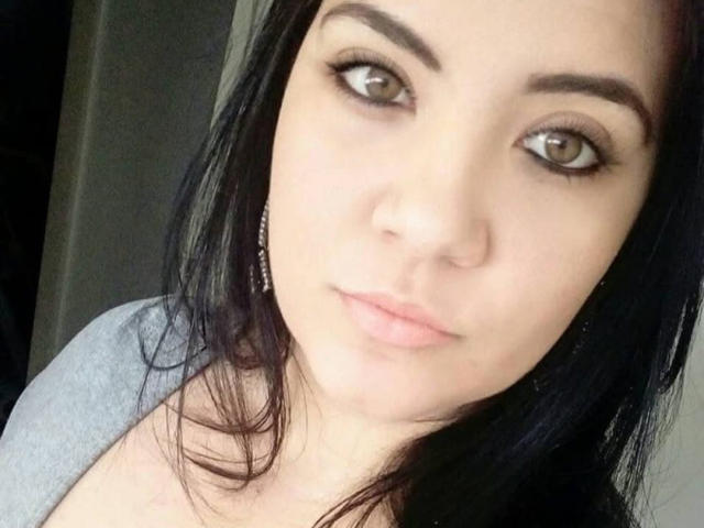 SafaDosDos has light brown eyes, dark eyebrows, and black hair. She's wearing a grey top with pink lips and small earrings, looking directly at the camera with a neutral expression.