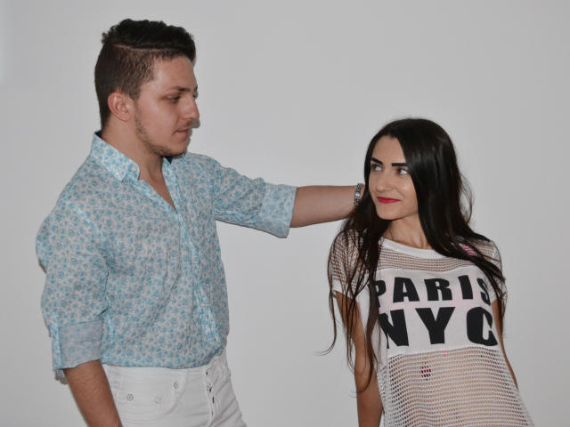 HotCoupleAnal: Homem com camisa floral azul, calças brancas, cabelo castanho curto, mão no cabelo da garota; garota com cabelo preto longo, lábios vermelhos, camisa listrada branca "Paris NYC".".