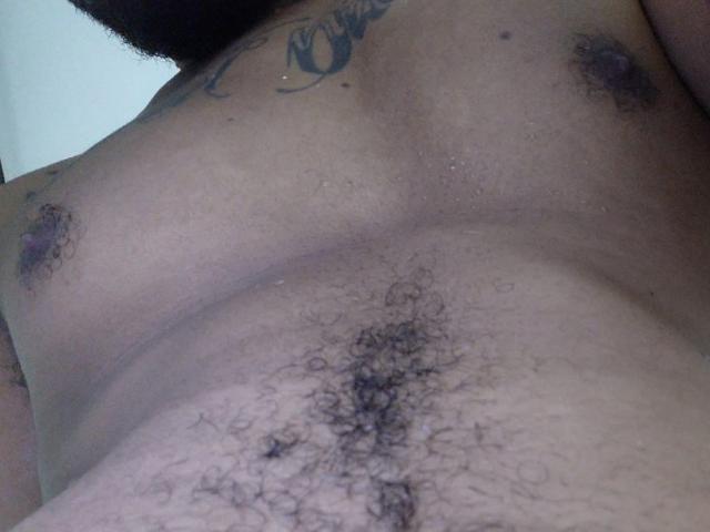 MorboErotico69's chest with small, dark nipples and a hairy, curly pubic region visible in the lower part of the image. Tattoos are present on the upper chest.