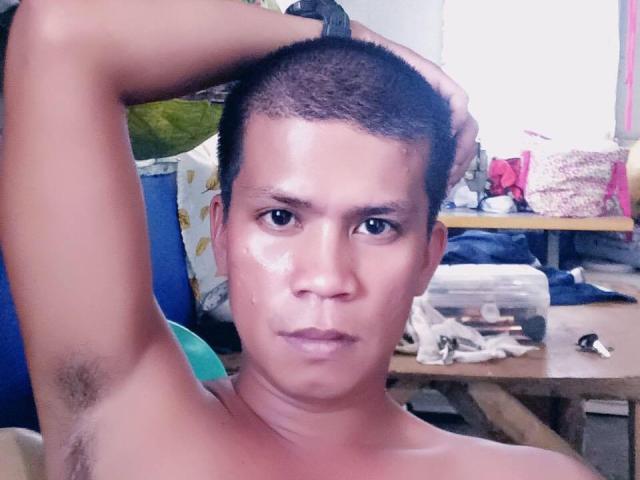 AsianHugox has short black hair, armpit hair, and a serious expression. He's shirtless with a glistening face, hand on head, and a slight wet spot on his nose.