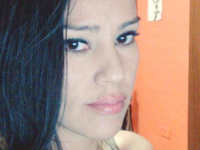 Abigail69 tiene el cabello oscuro y con aspecto húmedo, piel clara y labios rosados y gruesos, con un pequeño piercing en la nariz. Está mirando a la cámara con ojos azules y pestañas largas..