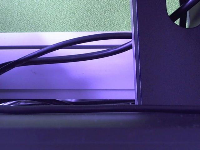 A bunch of black cables snaking over a white window sill, with a purple-blue light reflecting off the window. FlipFlops-hot's window.