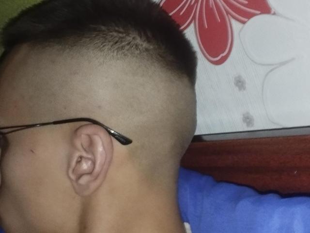 La cabeza afeitada de WinterBrian, con un moño, lleva gafas con una punta negra y está acostado, vistiendo una camisa azul. Se puede ver su oreja en el lado izquierdo..