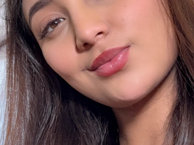 DianaFernandezz's face, showing a slight smile with pink, glossy lips, brown eyes, and long brown hair. Her skin is light and smooth. Her nose is small and cute.
