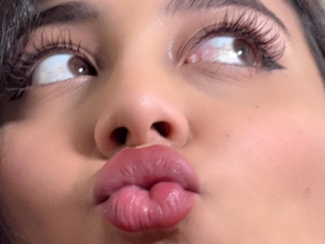 DianaFernandezz's face with brown eyes looking up, long eyelashes, and pink glossy lips puffed out like a kiss. Her nose is centered, and her skin is tan.