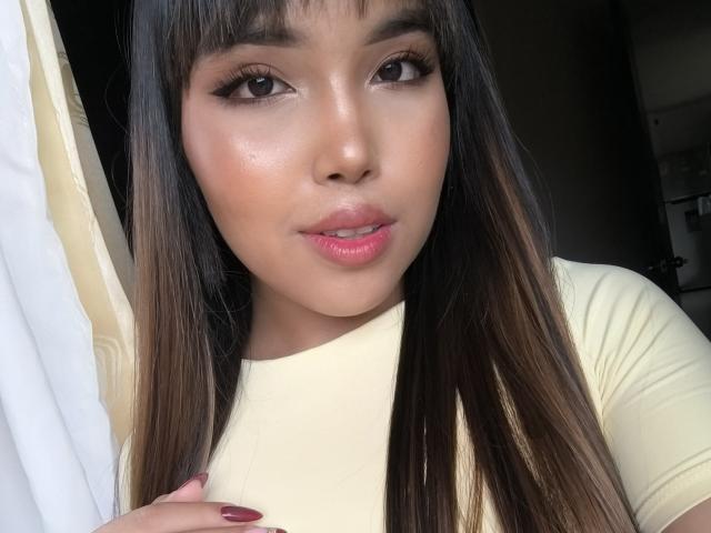 Heyly has glossy, full lips and straight black hair, looking seductively at the camera with flushed, shiny skin and dark eyes.