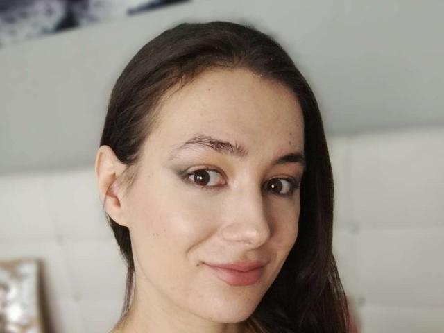 JuliaHuntis has light skin, brown eyes, dark brown straight hair, and a small nose. She's smiling slightly with a subtle, natural look. Her tits are not visible.