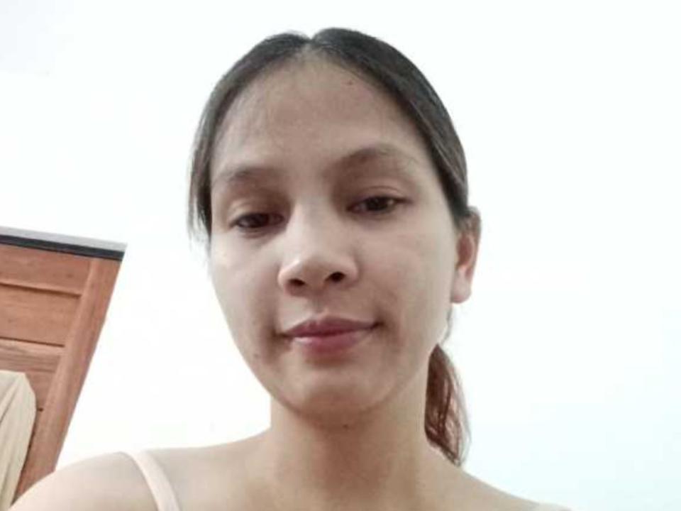 HotSexyTits with light brown skin, small nose, brown eyes, dark brown hair in a ponytail, smiling slightly, wearing a pink tank top, no visible boobs or ass.