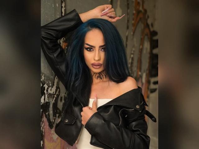 MassimoMillen with blue hair, black leather jacket, white dress, raised arm, seductive look, dark eyeliner, pink lips, holding jacket, slightly off-shoulder, sexy, tattooed neck.
