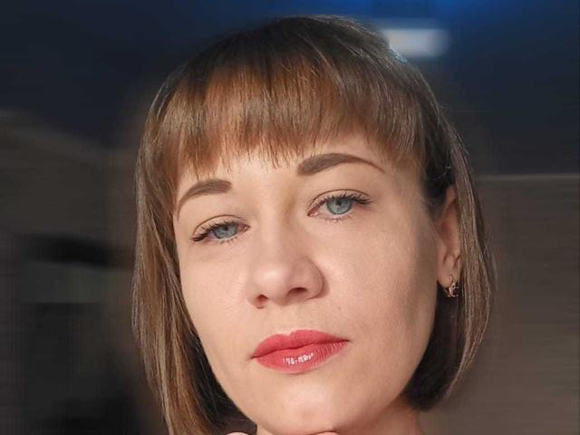 MarlynMartie has a cute face, short brown bob with bangs, blue eyes, red lipstick, and a small gold earring on her right ear. Her skin is fair.