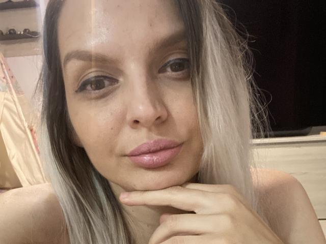 DouceAmelia has pouty pink lips, slightly glossy, with a light hand touching her chin. She's got dirty blonde hair, blue eyeshadow, and a neutral expression.